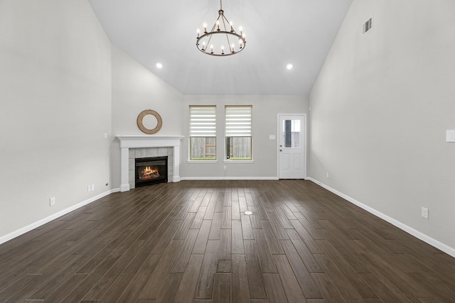 unfurnished living room with high vaulted ceiling, an inviting chandelier, baseboards, visible vents, and dark wood-style flooring
