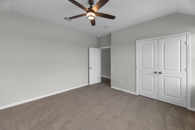 unfurnished bedroom featuring a closet, carpet floors, lofted ceiling, baseboards, and visible vents