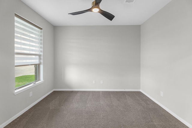 spare room featuring baseboards, visible vents, dark colored carpet, and ceiling fan
