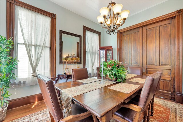 dining space with baseboards, wood finished floors, and a chandelier