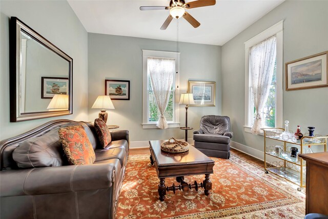 living room with baseboards, wood finished floors, and a ceiling fan