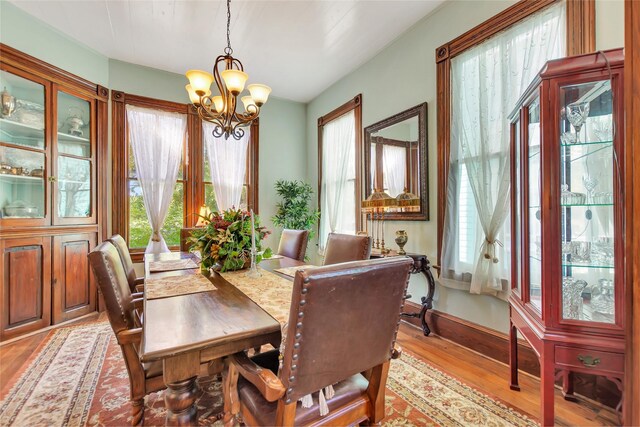 dining room featuring baseboards, light wood-type flooring, and a chandelier