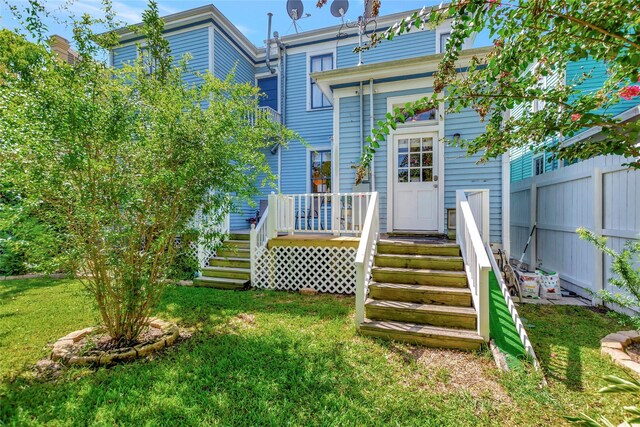 back of house featuring a wooden deck, fence, and a lawn
