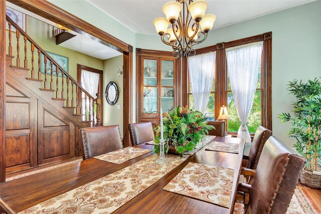 dining area with stairs, ornamental molding, wood finished floors, and an inviting chandelier