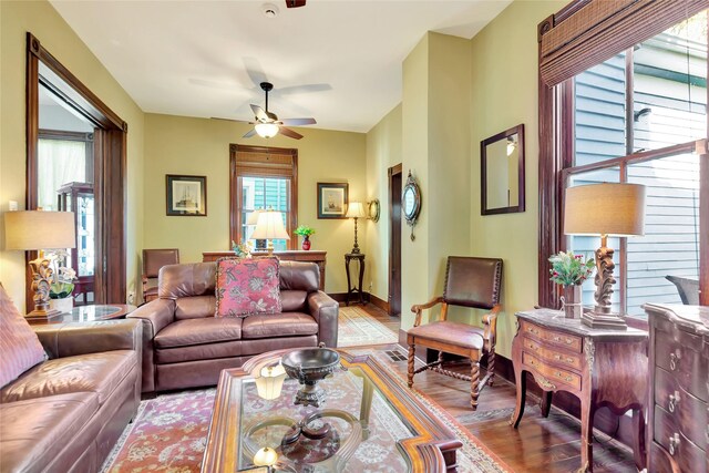 living room with baseboards, ceiling fan, and wood finished floors