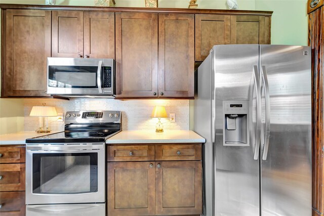 kitchen with light countertops, brown cabinets, stainless steel appliances, and backsplash