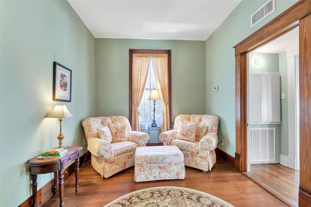 living area with baseboards, visible vents, and wood finished floors