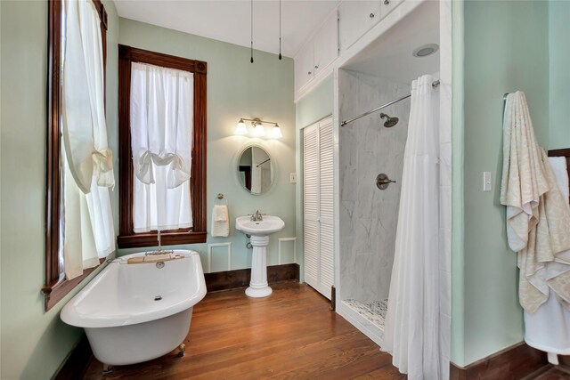 bathroom with a soaking tub, baseboards, a tile shower, and wood finished floors
