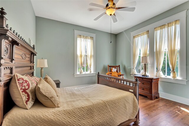 bedroom with multiple windows, wood finished floors, ceiling fan, and baseboards