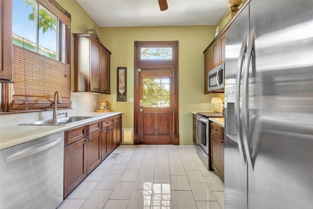 kitchen featuring light countertops, a sink, stainless steel appliances, and decorative backsplash