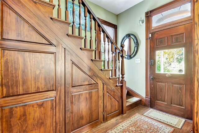 foyer entrance featuring baseboards, stairs, and wood finished floors