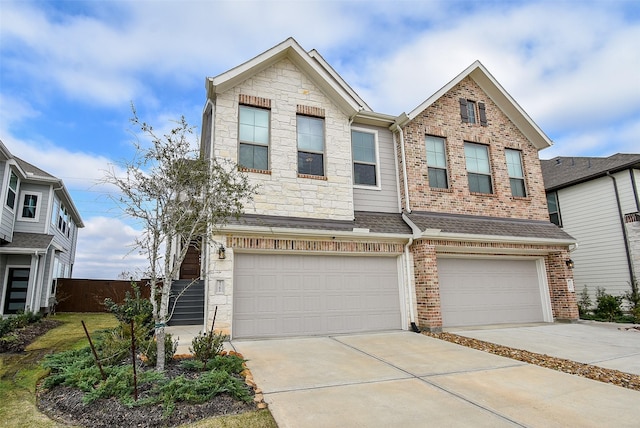 townhome / multi-family property featuring driveway, a shingled roof, a garage, and stone siding