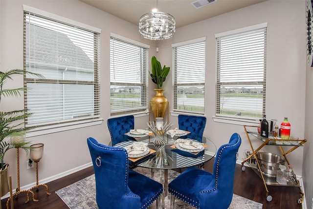 dining space with baseboards, visible vents, wood finished floors, and a notable chandelier