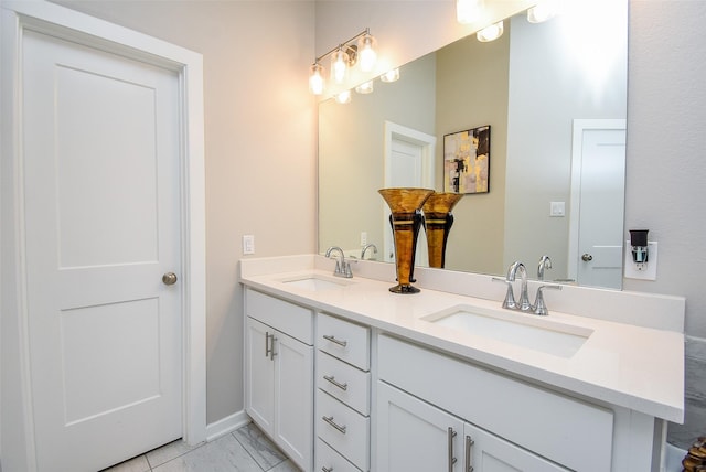 full bath featuring marble finish floor, double vanity, and a sink