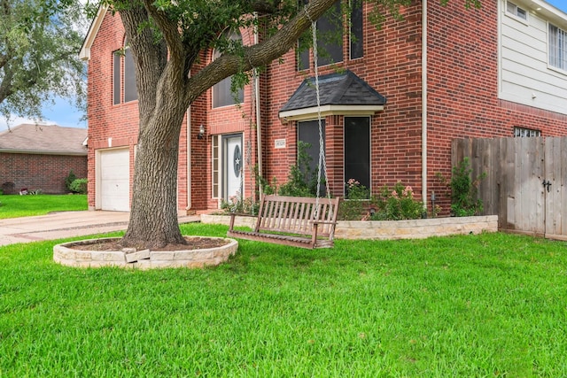 view of front of house with an attached garage, brick siding, fence, and a front yard