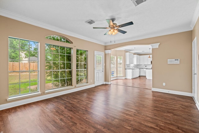 unfurnished living room with ceiling fan, visible vents, crown molding, baseboards, and dark wood-type flooring