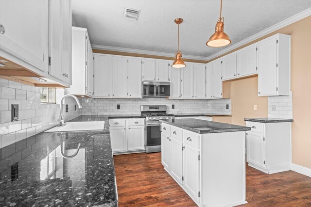kitchen featuring crown molding, appliances with stainless steel finishes, a sink, dark stone countertops, and visible vents