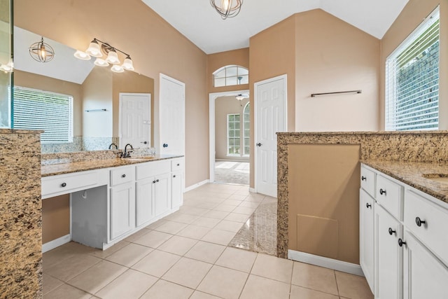 bathroom with a sink, lofted ceiling, tile patterned floors, and two vanities