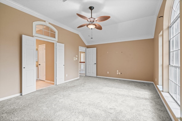 unfurnished bedroom featuring carpet floors, a ceiling fan, baseboards, vaulted ceiling, and ornamental molding