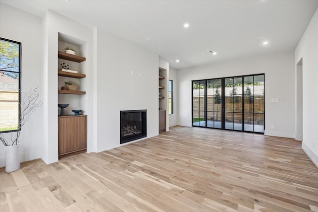 519 Milwaukee St, Houston, TX 77009 - unfurnished living room with light wood finished floors, a glass covered fireplace, built in features, baseboards, and recessed lighting