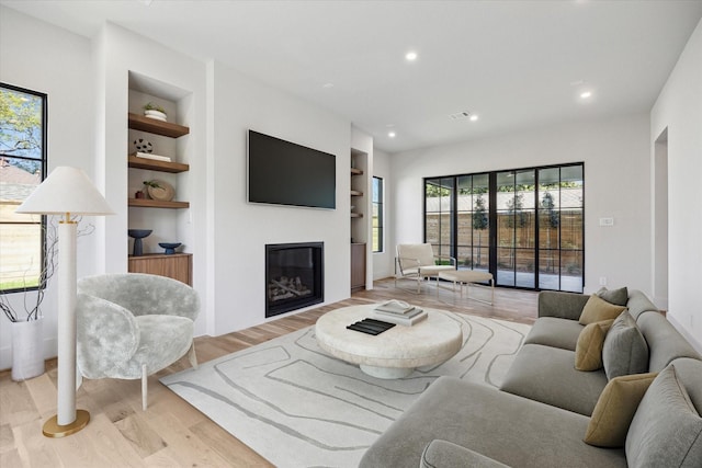 519 Milwaukee St, Houston, TX 77009 - living area featuring recessed lighting, light wood-style flooring, built in shelves, and a glass covered fireplace