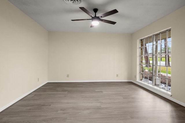 empty room with wood finished floors, visible vents, baseboards, and ceiling fan