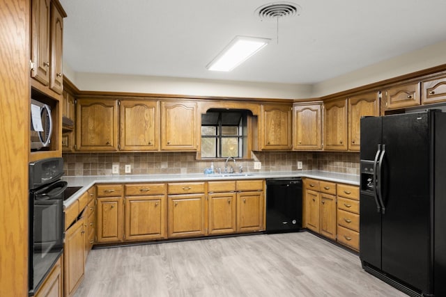 kitchen with a sink, visible vents, black appliances, and brown cabinetry