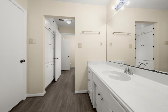 bathroom featuring baseboards, visible vents, wood finished floors, and vanity