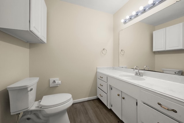 half bathroom with baseboards, toilet, vanity, and wood finished floors