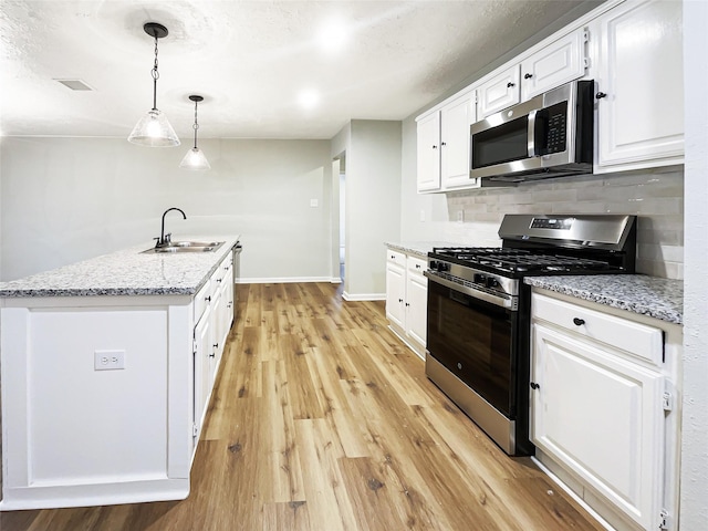 kitchen featuring white cabinetry, light wood-type flooring, stainless steel appliances, decorative backsplash, and a sink