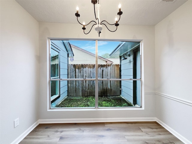 unfurnished dining area featuring wood finished floors, an inviting chandelier, and plenty of natural light