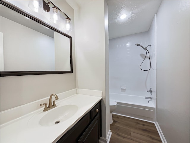 bathroom featuring a textured ceiling, tub / shower combination, toilet, wood finished floors, and vanity