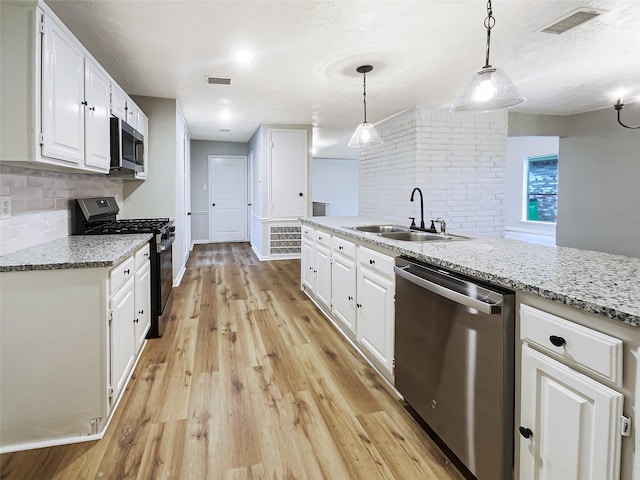 kitchen with light wood-style flooring, stainless steel appliances, decorative backsplash, a sink, and white cabinets
