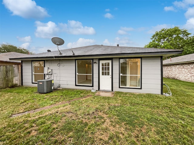 back of house with central AC unit, fence, and a yard