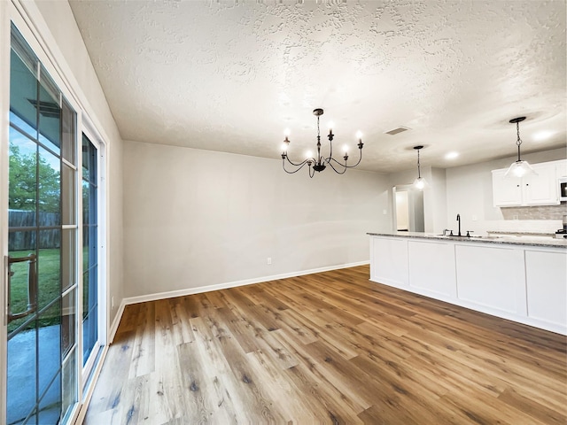 kitchen with white cabinetry, wood finished floors, a textured ceiling, and visible vents