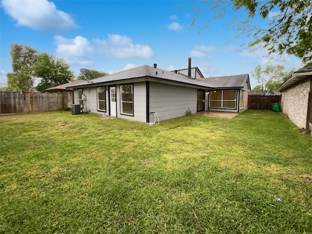 rear view of property with a fenced backyard, central AC unit, and a lawn