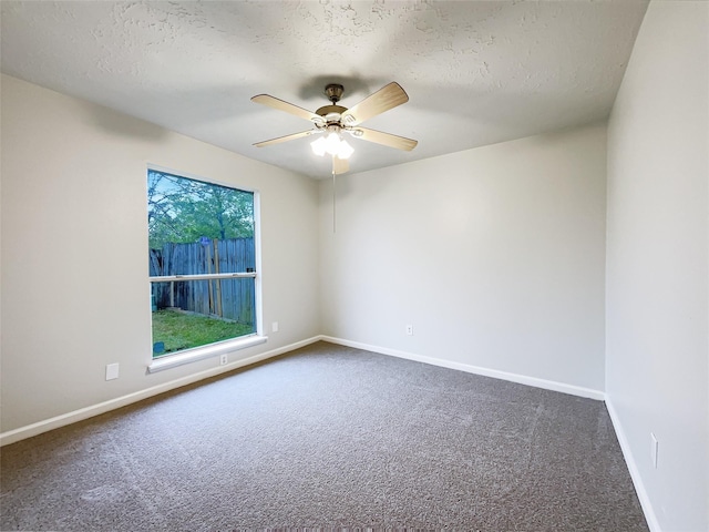 spare room with baseboards, a textured ceiling, dark carpet, and a ceiling fan
