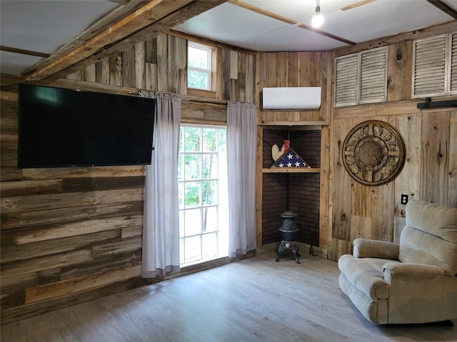 interior space with an AC wall unit, wooden walls, a wood stove, and wood finished floors