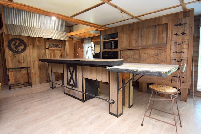 kitchen featuring light wood finished floors, black appliances, wood walls, and open shelves