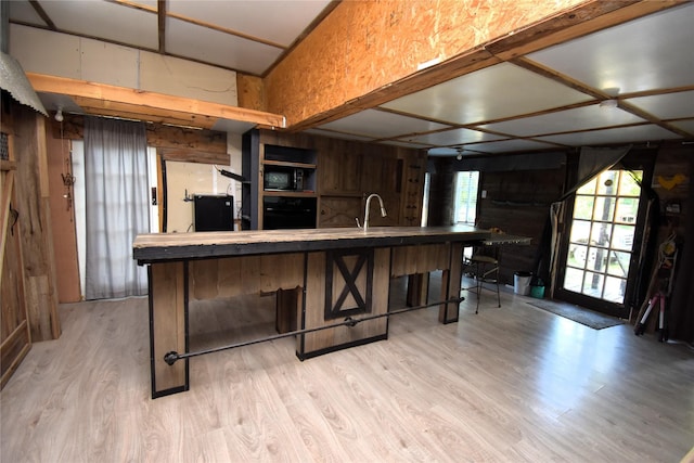 kitchen featuring black appliances, light wood-style floors, a sink, and a healthy amount of sunlight