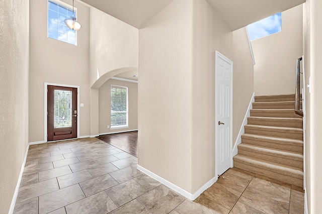 entryway featuring arched walkways, a high ceiling, and baseboards