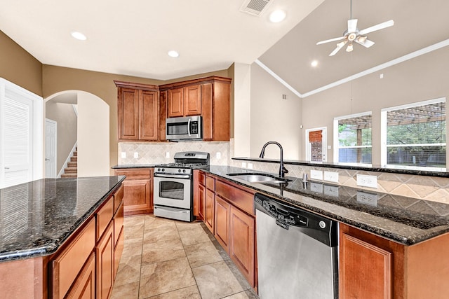 kitchen with brown cabinetry, visible vents, arched walkways, a sink, and stainless steel appliances