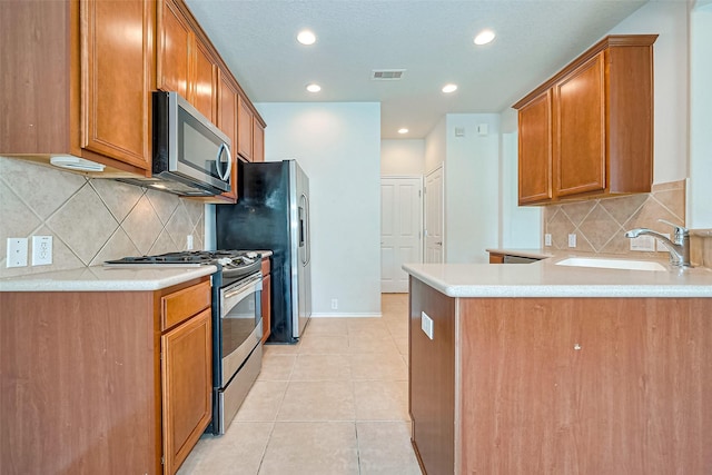 13600 Breton Ridge St Unit 22D, Houston, TX 77070 - kitchen featuring appliances with stainless steel finishes, a sink, a peninsula, light tile patterned floors, and decorative backsplash