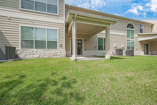 13600 Breton Ridge St Unit 22D, Houston, TX 77070 - rear view of house featuring central AC, stone siding, a lawn, and a patio area