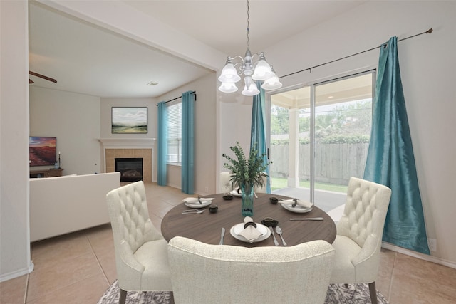 13600 Breton Ridge St Unit 22D, Houston, TX 77070 - dining area featuring light tile patterned floors, a chandelier, a tiled fireplace, and a ceiling fan