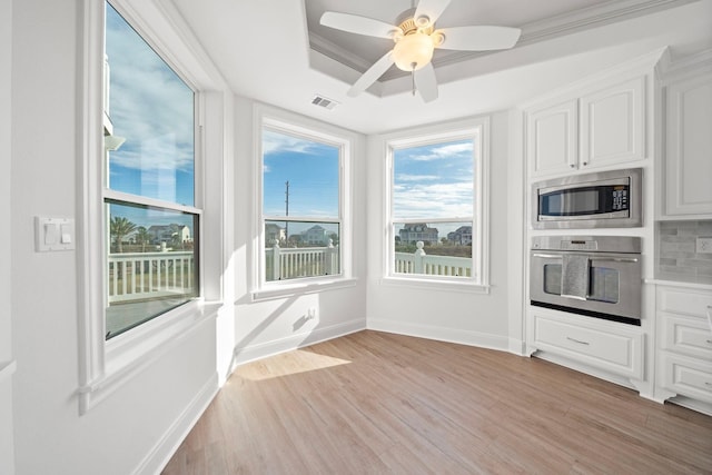 20919 W Sunset Bay Dr, Galveston, TX 77554 - kitchen featuring stainless steel appliances, light wood-style flooring, white cabinetry, a ceiling fan, and a raised ceiling