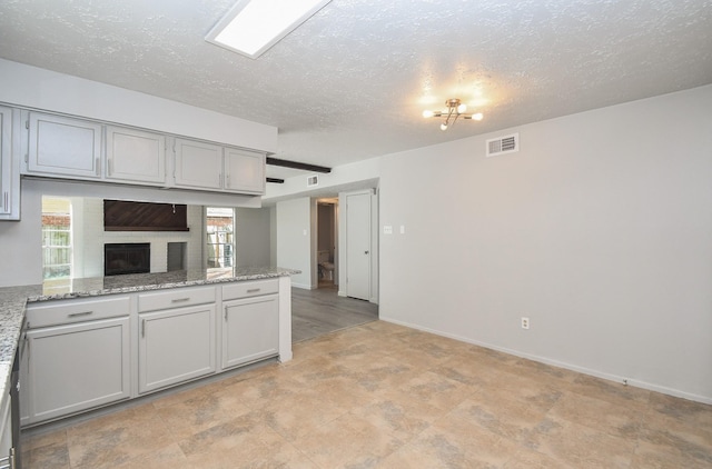 15827 Tammany Ln, Houston, TX 77082 - kitchen with gray cabinets, baseboards, a textured ceiling, visible vents, and a peninsula