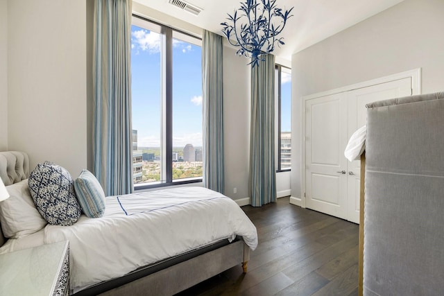 1409 Post Oak Blvd Unit 2702, Houston, TX 77056 - bedroom with an inviting chandelier, visible vents, a view of city, baseboards, and dark wood-style floors