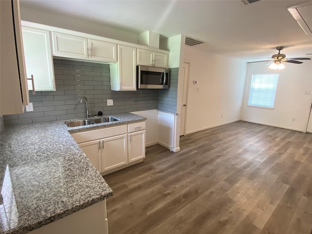 5217 Malmedy Rd A/B, Unit A/B Houston, TX 77033 - kitchen featuring stainless steel microwave, light stone countertops, white cabinetry, and backsplash