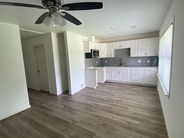 5217 Malmedy Rd A/B, Unit A/B Houston, TX 77033 - kitchen featuring stainless steel microwave, decorative backsplash, a ceiling fan, white cabinets, and wood finished floors